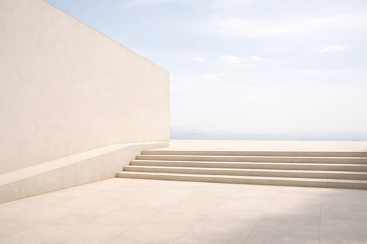 Helle, moderne Architekturfläche aus Beton und Putz im weichen Mittagslicht. Eine breite, flache Treppe führt über eine ruhige, offene Fläche ohne Menschen oder Objekte. Kaum Schatten, gleichmäßige Helligkeit,