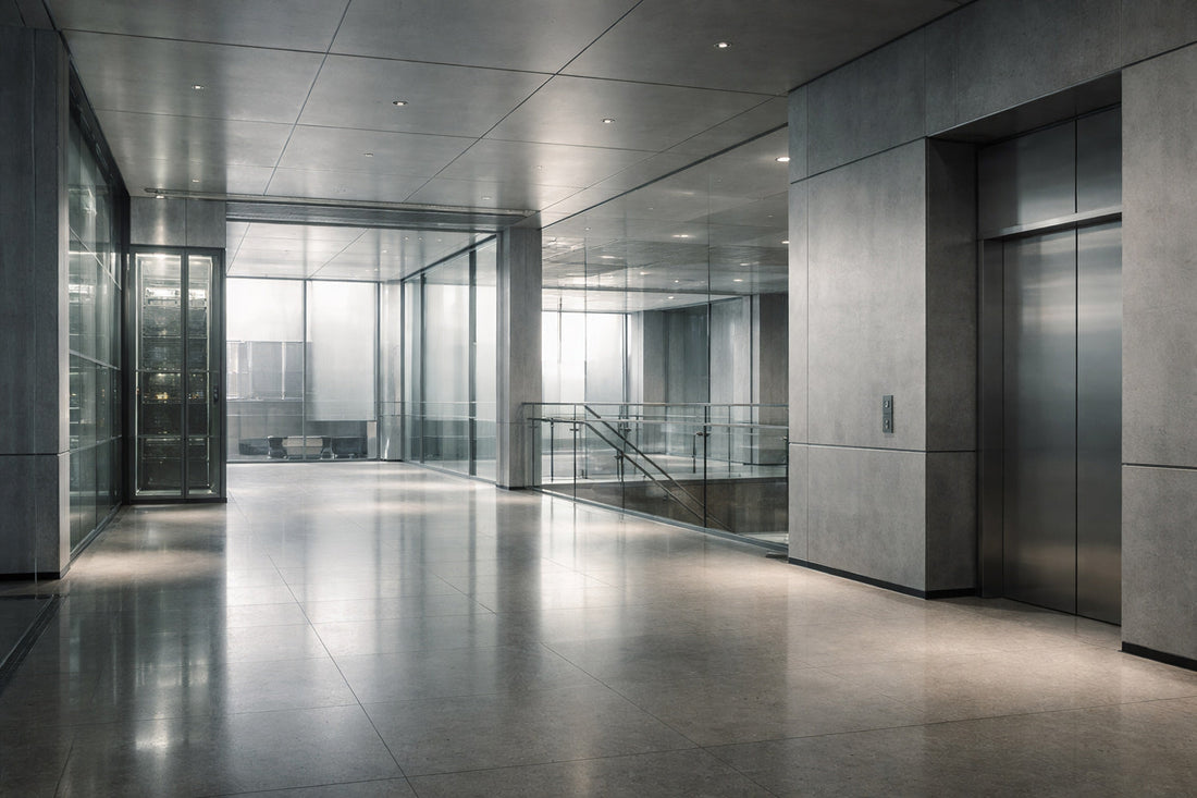 Leerer, technischer Innenraum in luxuriöser Architektur mit Beton, Glas und Metall. Diffuses, neutrales Nachmittagslicht fällt auf offene Flächen und glatte Oberflächen. Keine Menschen, keine Bewegung.