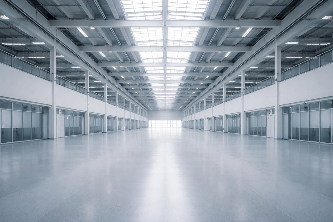 Große, moderne Halle mit serieller Architektur und gleichmäßigem Tageslicht von oben. Die symmetrische Struktur aus Stahl, Glas und Beton wirkt offen, richtungslos und leer – ein Raum ohne Markierung.