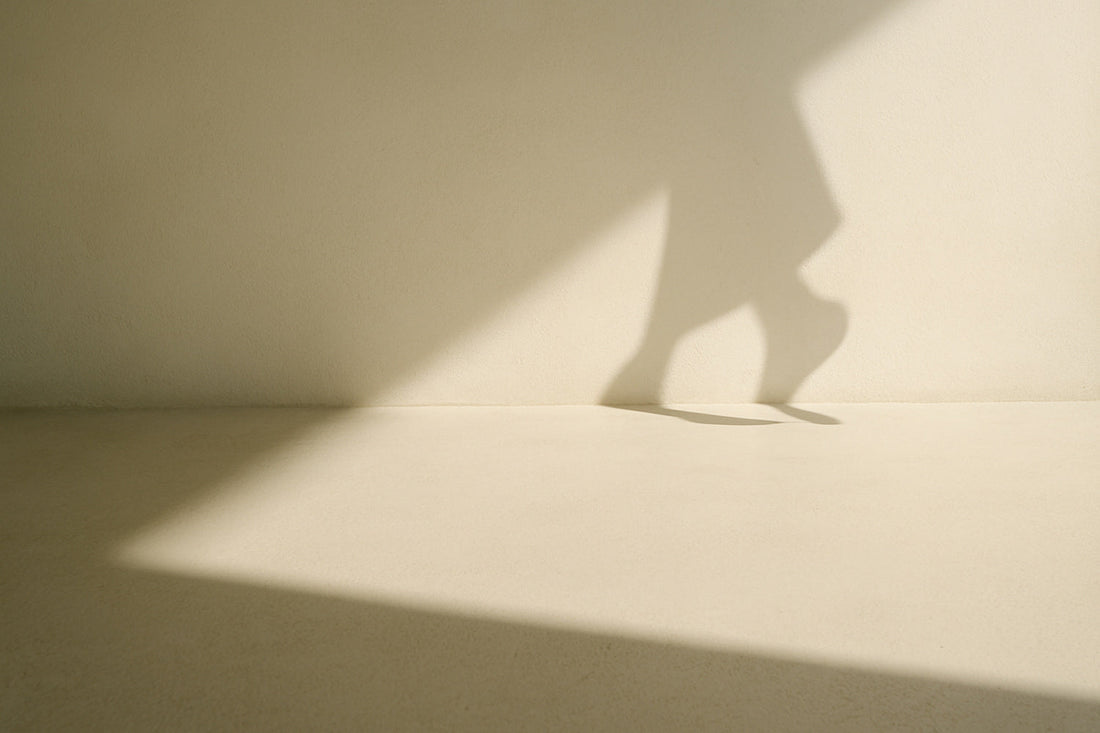 Helle, offene Fläche mit sanften Schatten, die einen Moment des Übergangs und der stillen Bewegung zwischen zwei Schritten andeutet.
