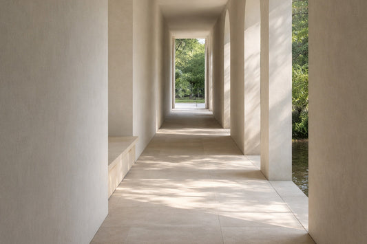 Heller, minimalistischer Übergangsgang mit sanftem Tageslicht, cremefarbenen Wänden und Bögen, die in einen offenen Außenraum führen; ruhige Architektur ohne Zielpunkt, geprägt von Licht und Schatten