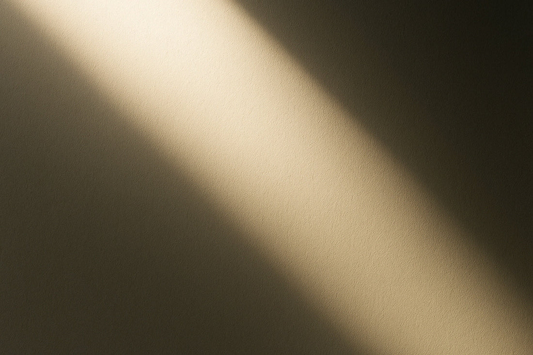 Diagonal fallender Lichtstrahl auf einer weichen, dunklen Fläche – ein minimalistisches Spiel aus Schatten und Helligkeit, das Ruhe, Tiefe und Zwischenräume erzeugt