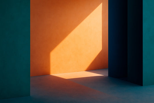 Eine farbintensive, minimalistische Szene: Eine leuchtend orange Wand wird von einem scharfkantigen Lichtdreieck erfasst. Links und rechts stehen hohe, türkis- und dunkelblau gefärbte architektonische Elemente.