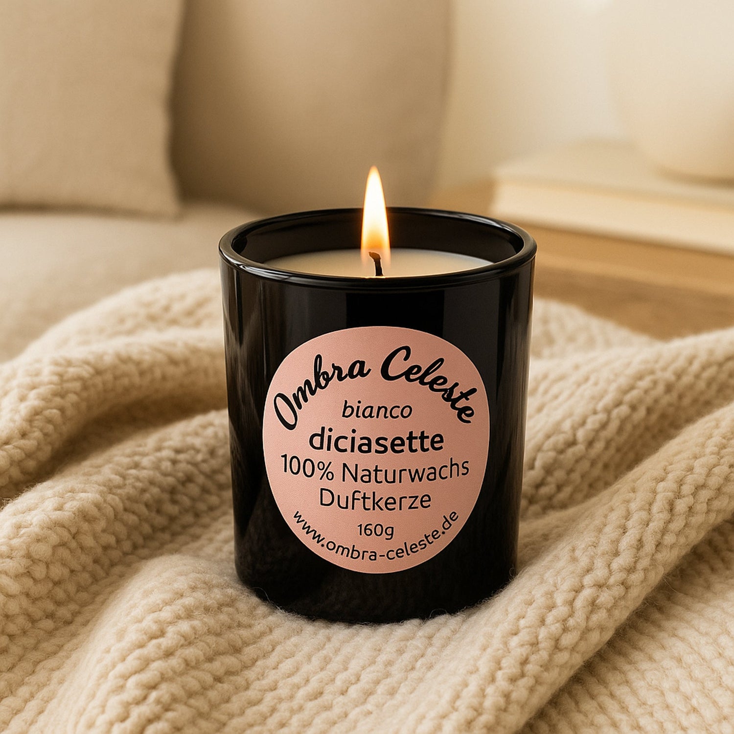 Schwarze Duftkerze Ombra Celeste bianco diciasette aus 100% Naturwachs, brennend auf einer beigen Decke, 160 gr